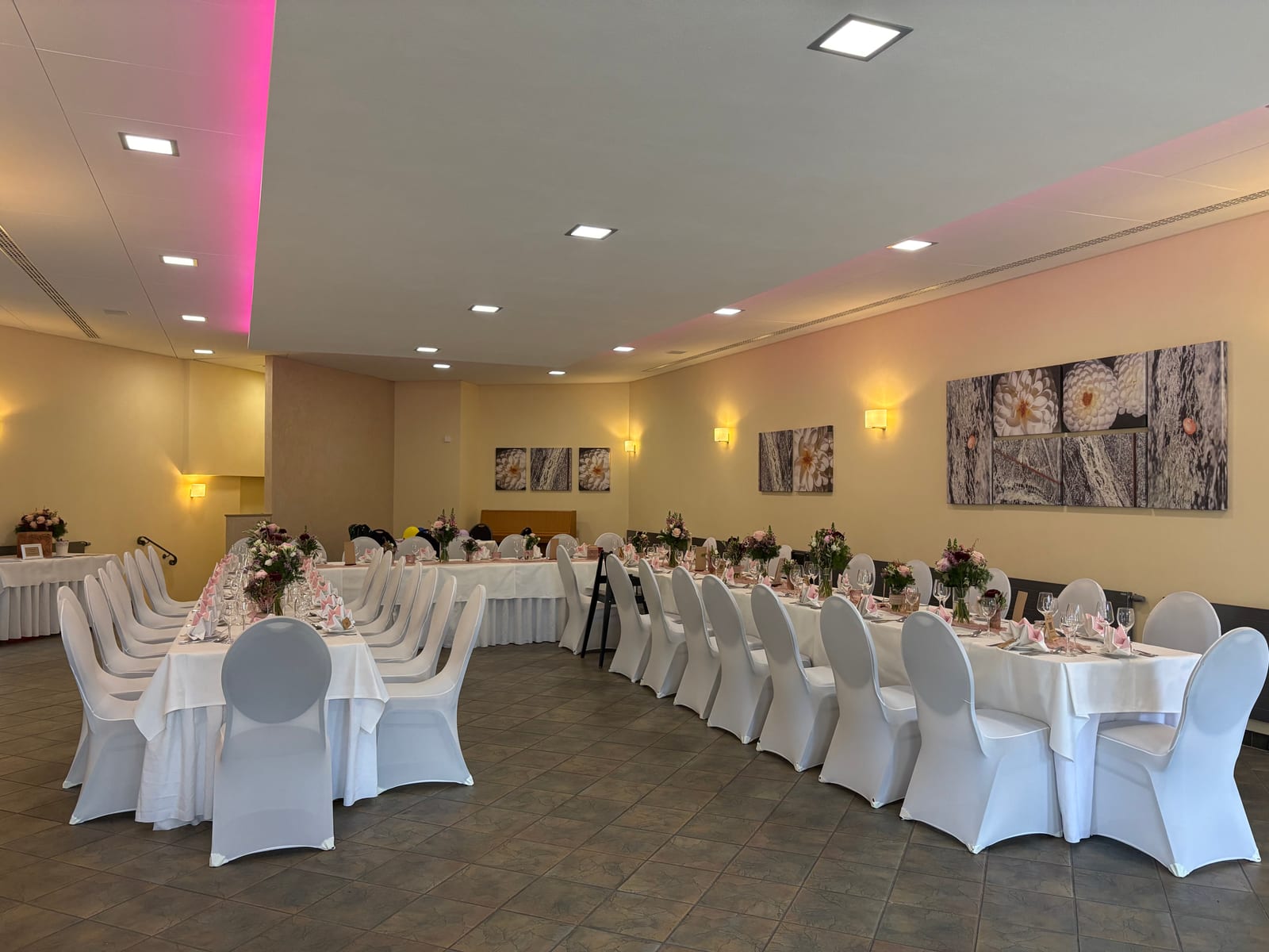 Festlich gedeckte Tafeln im Saal mit Blick zur Terrasse